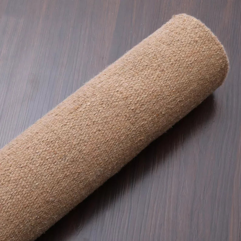 Tan flatweave Kilim wool rug rolled edge on dark floor