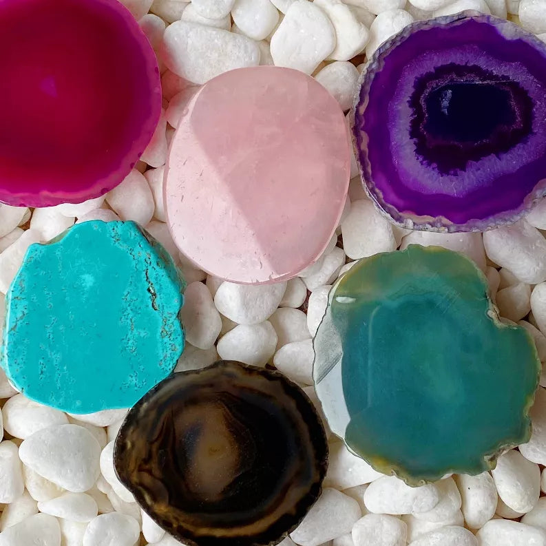 Colorful agate phone grips—fuchsia, pink, purple, teal—on white pebbles