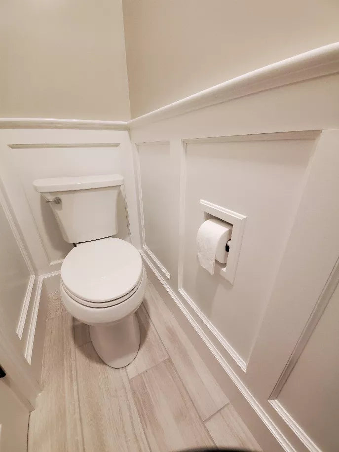 Recessed toilet paper holder in white trim with paper roll mounted on wall