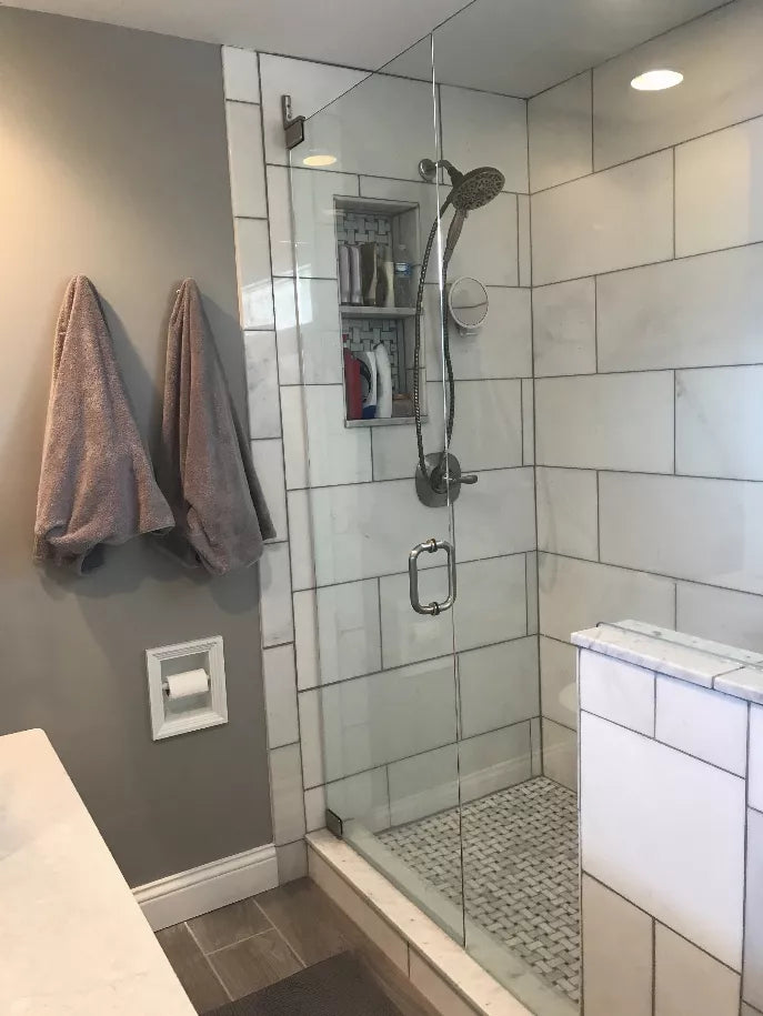 Installed recessed toilet paper holder with small framed opening on bathroom wall