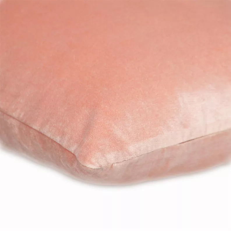 Pink throw pillow corner seam close-up with smooth textured fabric.