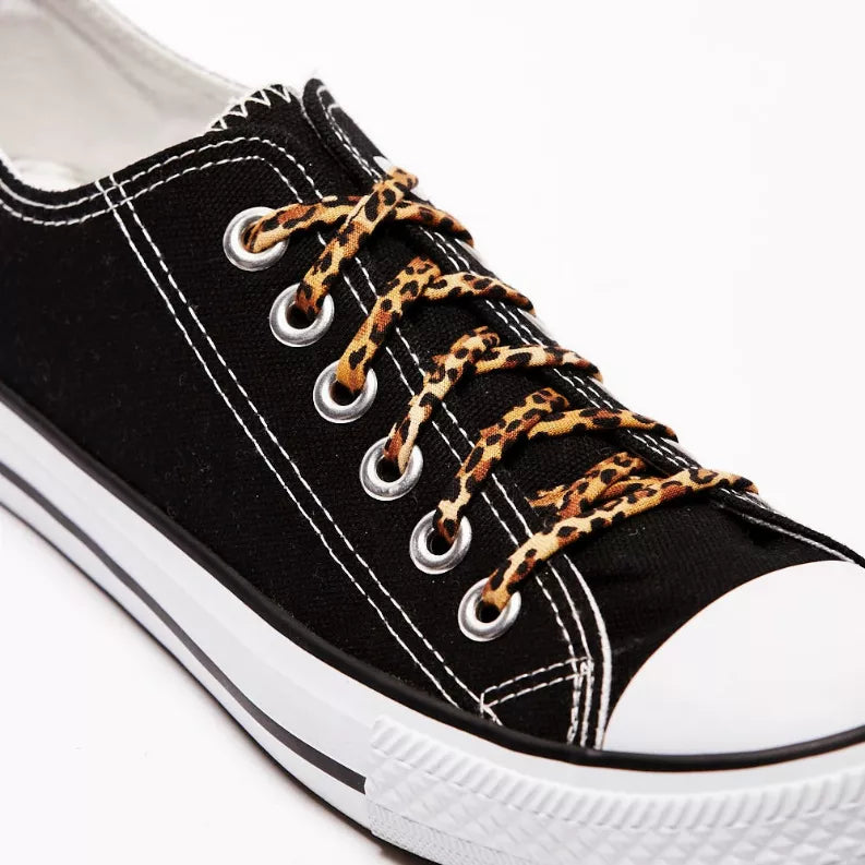 Black sneaker with leopard-print shoelaces and round metal eyelets