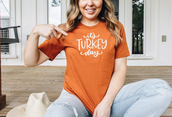 Orange crewneck T-shirt with white "It's Turkey Day" text graphic