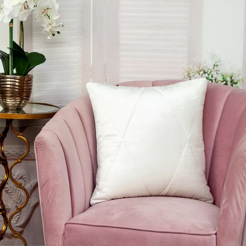 White quilted throw pillow centered on a pink armchair, stitched square front