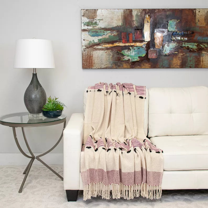 Beige and mauve woven throw blanket with striped bands and long fringe, on a sofa