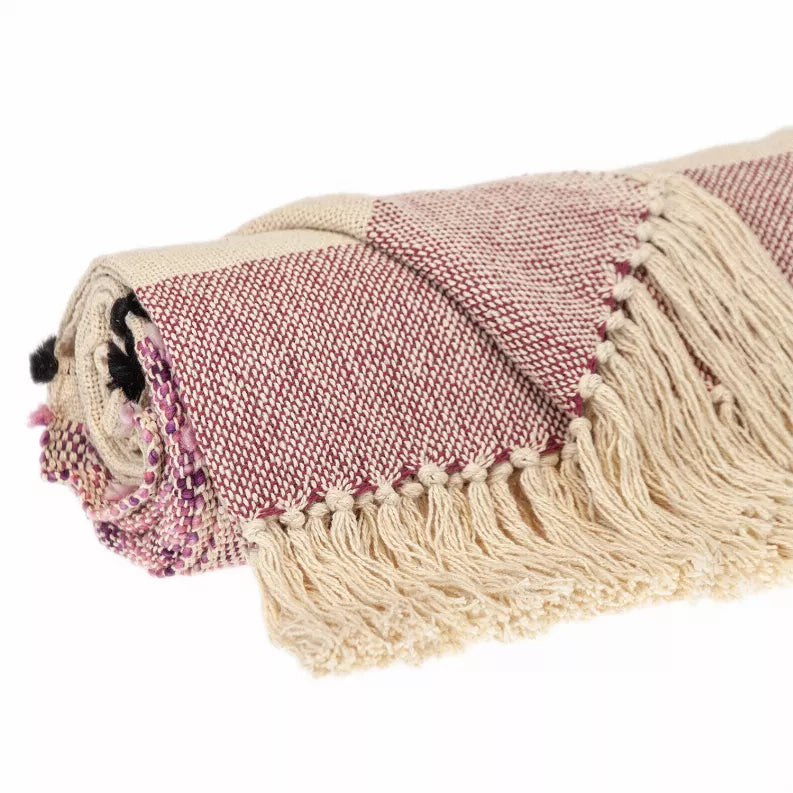 Close view of beige and mauve woven throw with cream fringe border and pom details