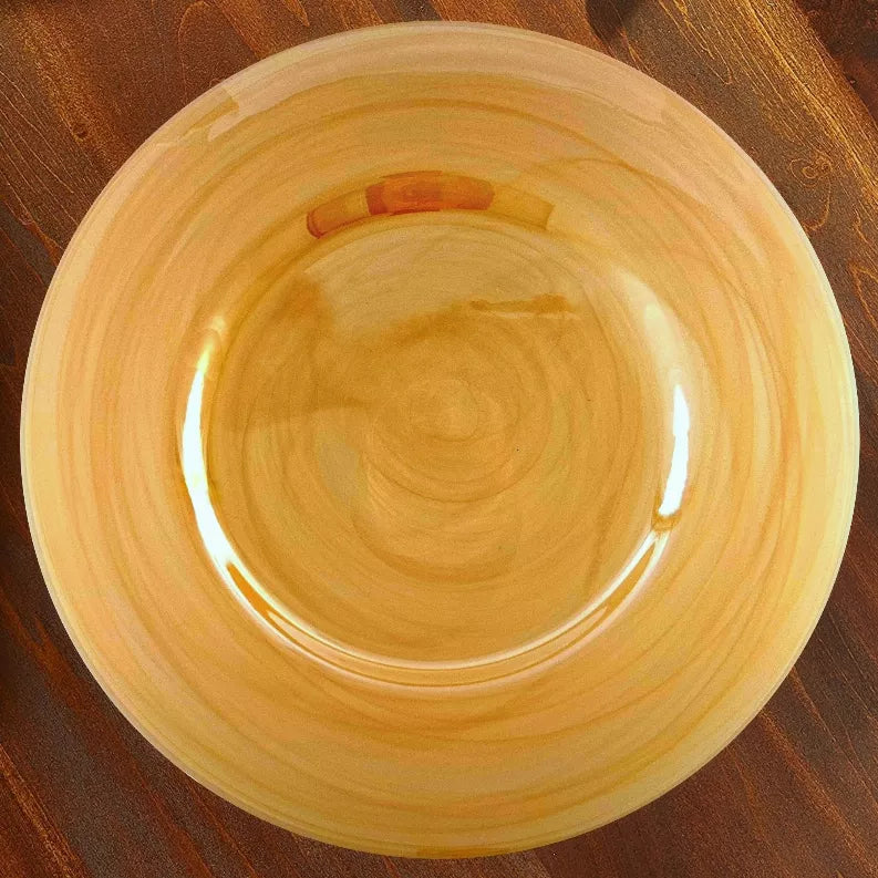 Amber glass charger plate with glossy finish and subtle spiral pattern