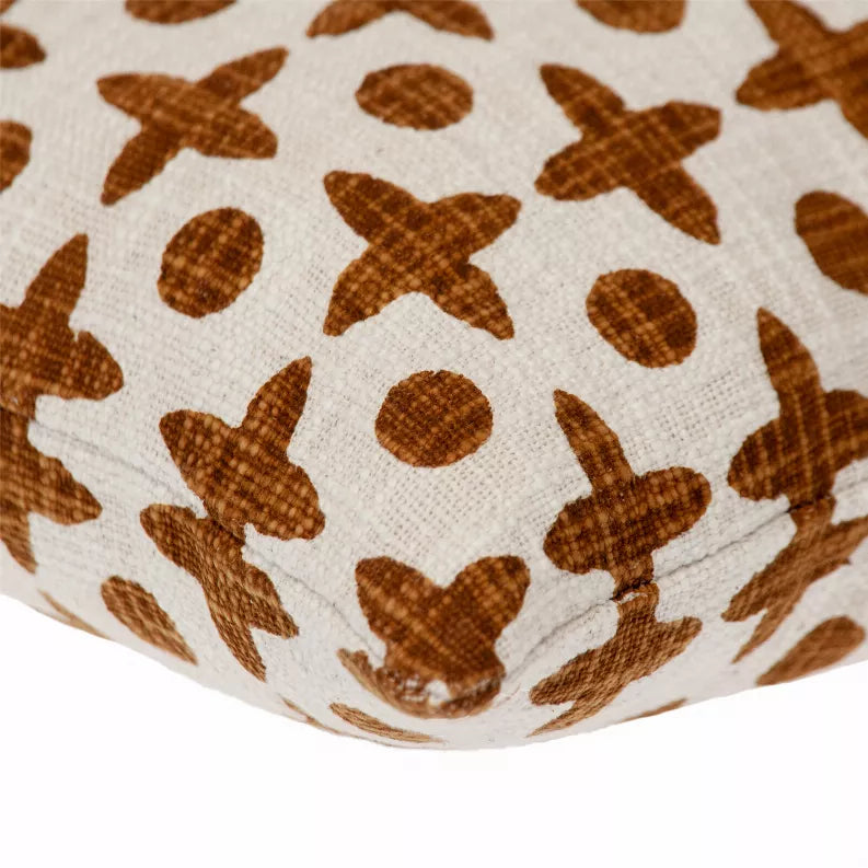 Close-up of brown geometric cross and dot pattern on cream woven pillow fabric