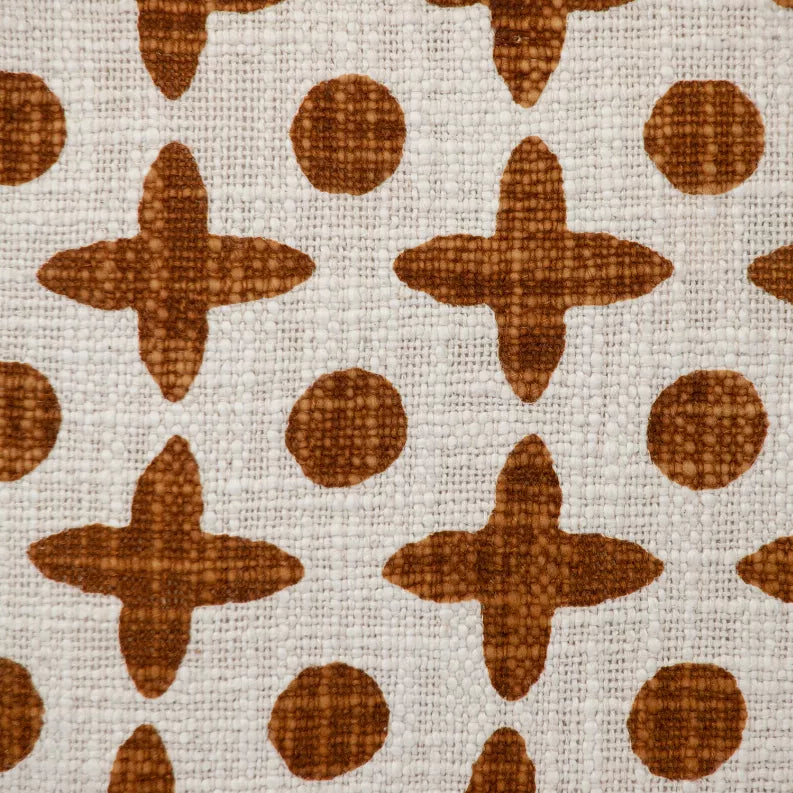 Texture close-up of cream fabric with brown geometric crosses and dots pattern