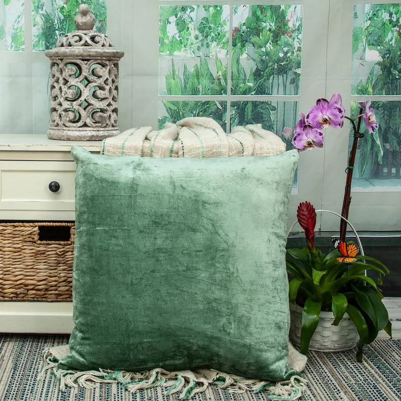 Green solid square throw pillow in a room setting with textured velvet-like cover
