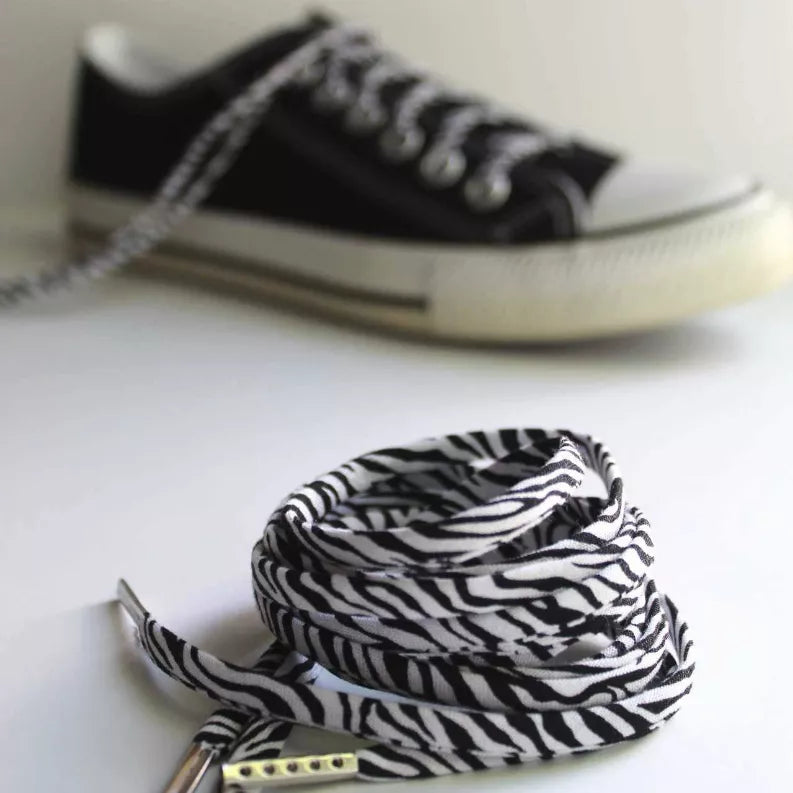 Zebra-pattern shoelaces lying flat with silver aglets