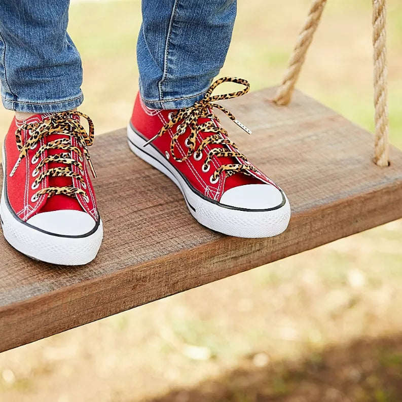 Red canvas sneakers with leopard-print shoelaces and metal eyelets