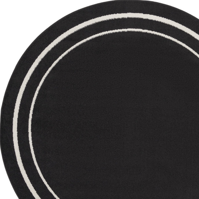 Round black area rug with ivory concentric circles, dark center and double border rings