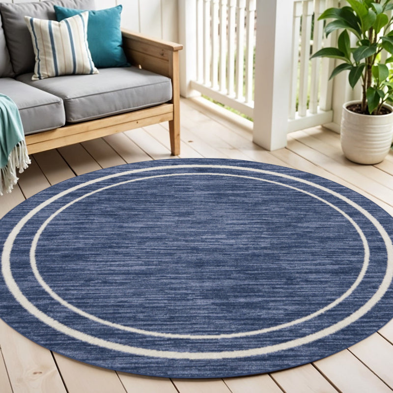Round navy blue rug featuring ivory concentric rings over a textured surface.
