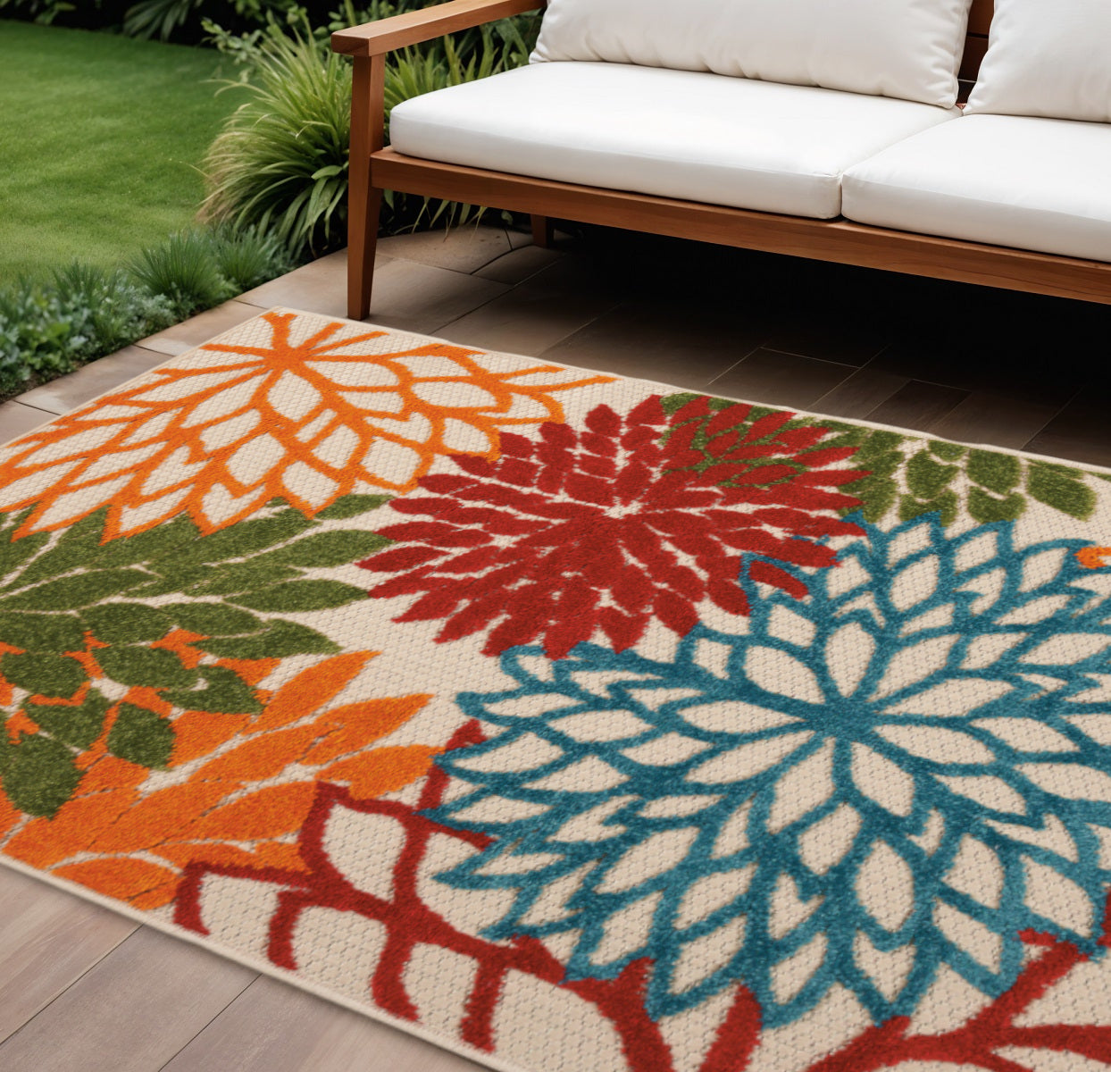 Outdoor floral area rug with large orange, red, and blue flower motifs on ivory