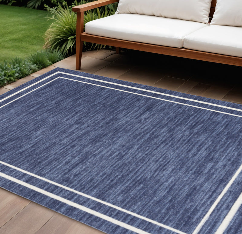 Navy and ivory indoor outdoor area rug with striped border, laid on wood