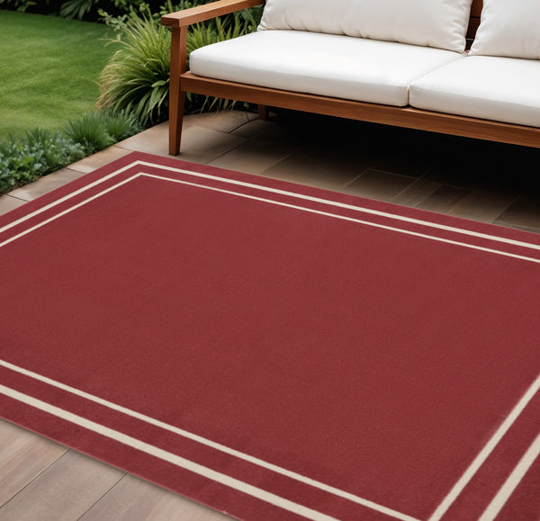 Brick red and ivory indoor/outdoor area rug with bordered geometric trim, corner view