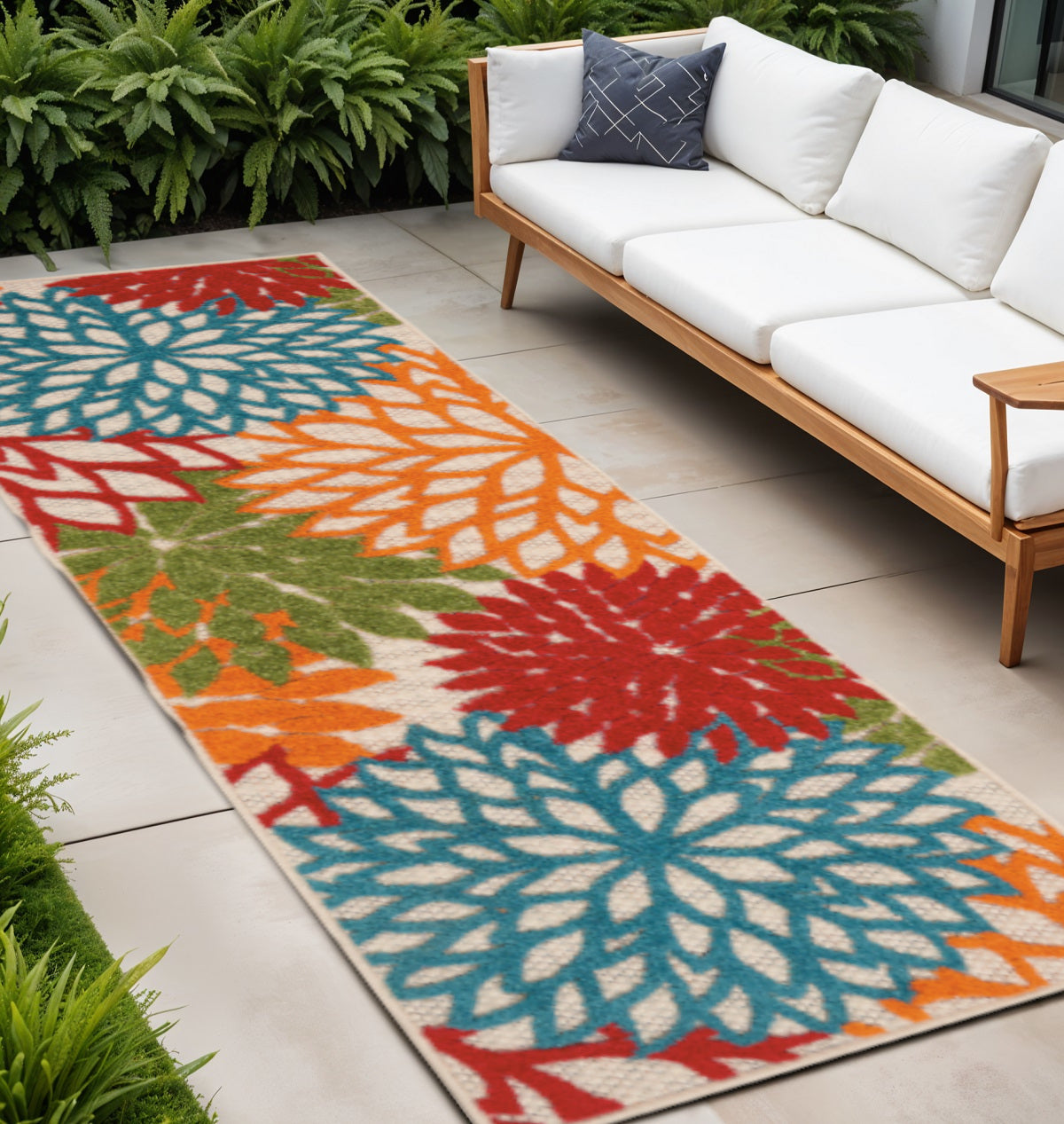 Colorful floral outdoor runner rug with blue, orange, and red starburst patterns on patio tile.