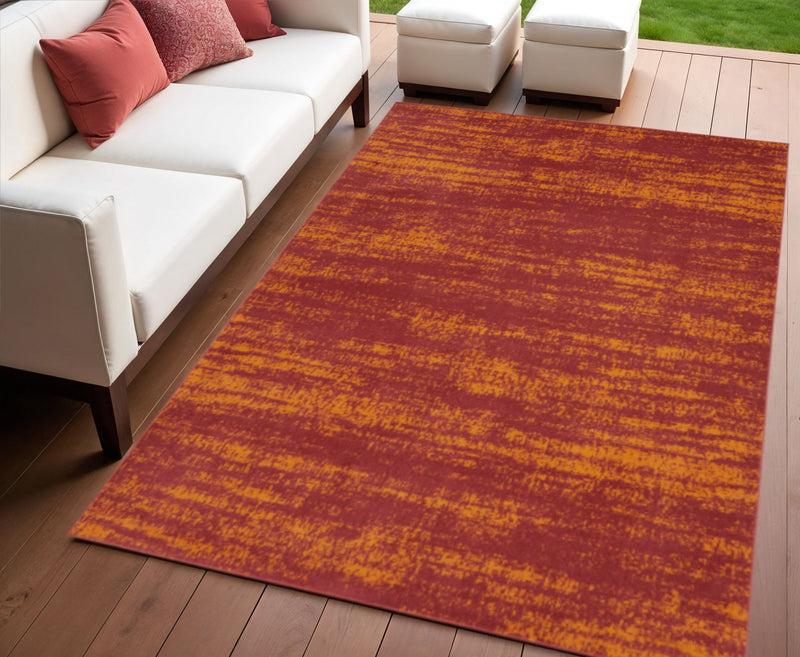 Red and orange abstract indoor outdoor area rug on hardwood floor