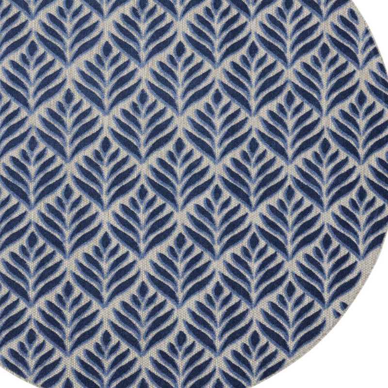Close-up of round blue rug with cream background and leaf motif