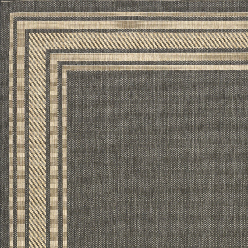 Charcoal area rug corner with beige and dark stripe border framing a center panel
