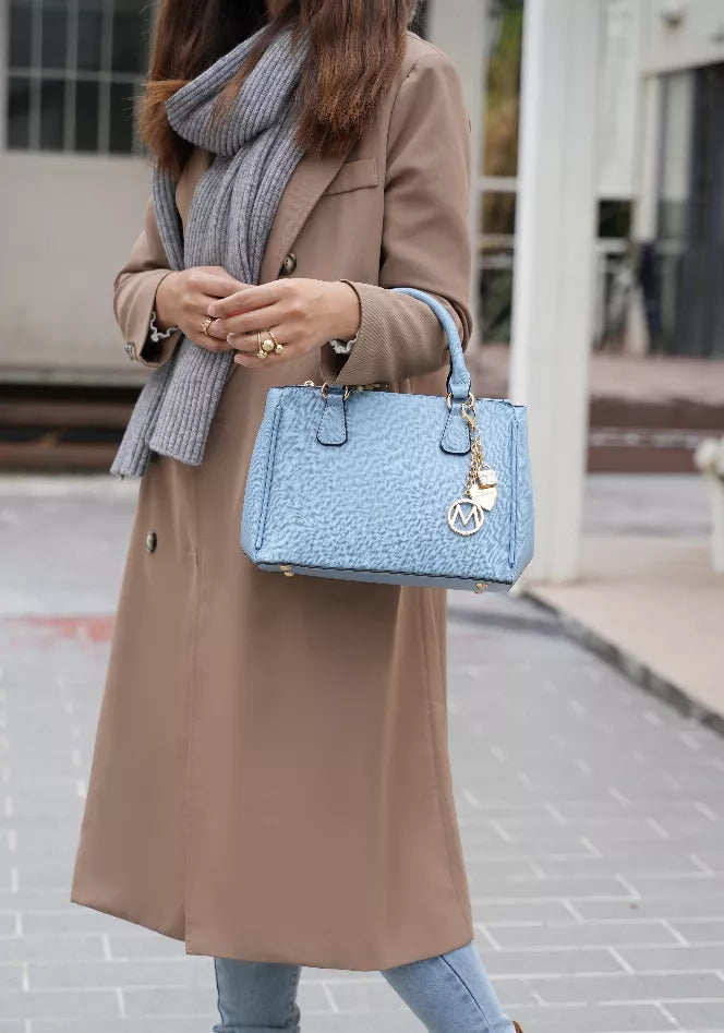 Light blue satchel bag with top handles, chain charm, and subtle textured finish