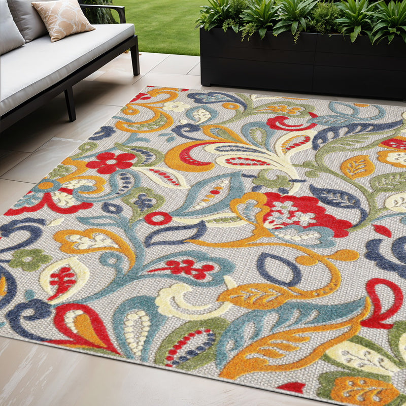 Multi-color Jacobean floral area rug in an outdoor seating area with plants and sofa
