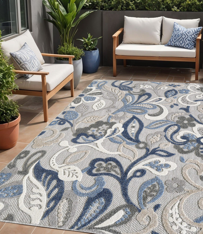 Indoor/outdoor area rug in gray with blue and white floral scroll pattern, corner view