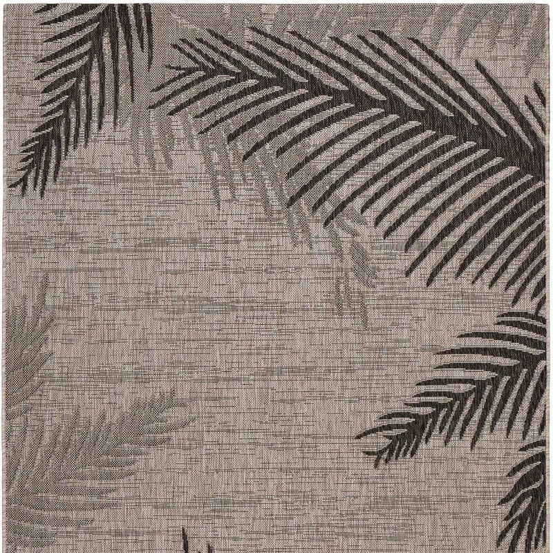 Beige area rug featuring black palm frond leaf pattern on textured surface
