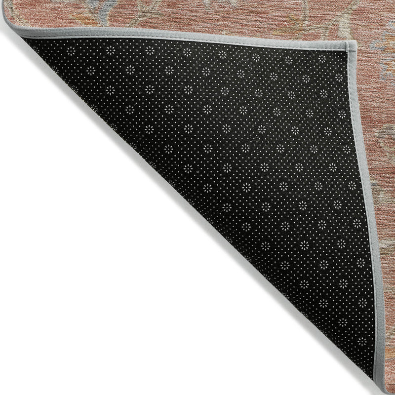 Reversible-style edge view: pink rug top with dark gray/black dotted backing