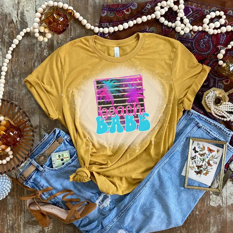 Mustard yellow crew-neck T-shirt with centered neon beach graphic and glittery print specks
