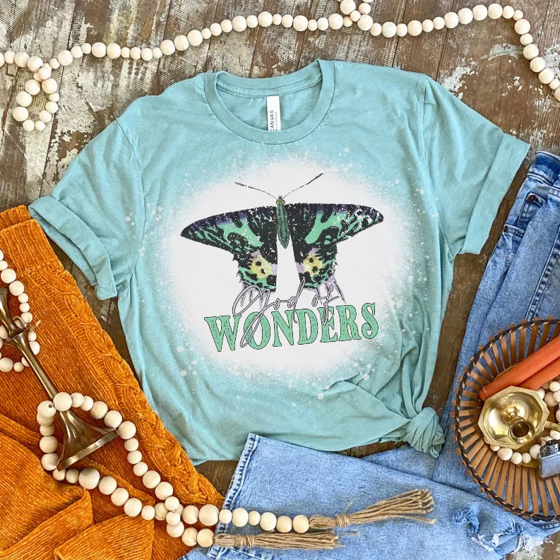 Teal short-sleeve T-shirt with butterfly graphic and 'Wonders' text