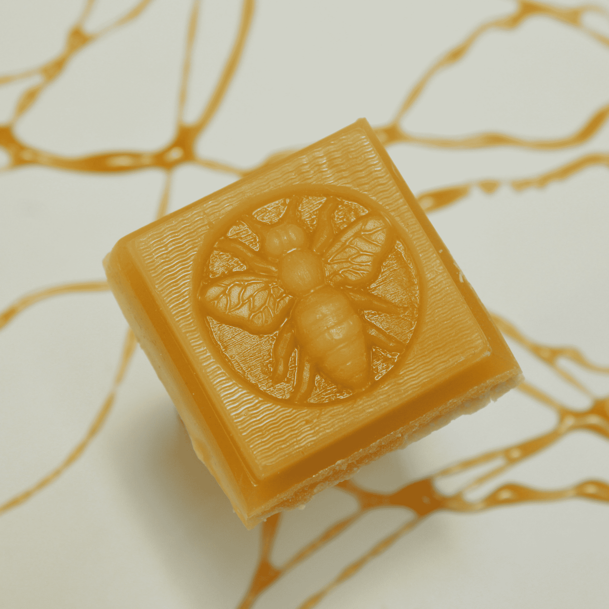 Amber beeswax soap bar with embossed flower-and-bee design