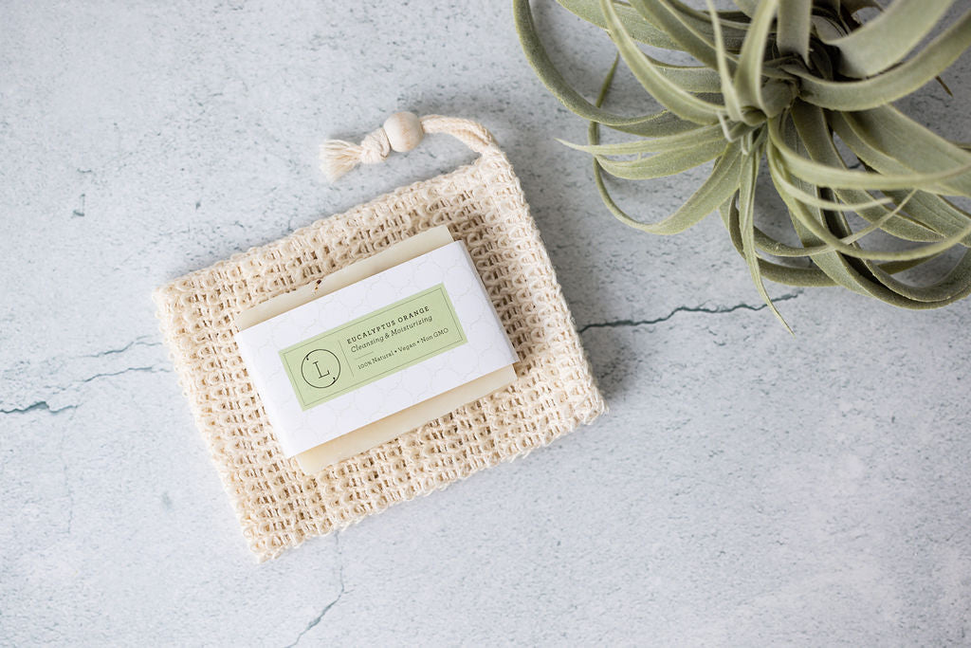 Handmade soap bar in jute pouch with white label, wrapped square, top view