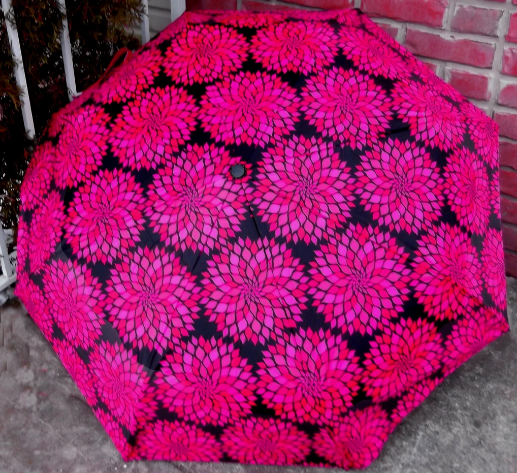 Compact umbrella canopy with pink-and-black floral mosaic pattern, centered button detail.