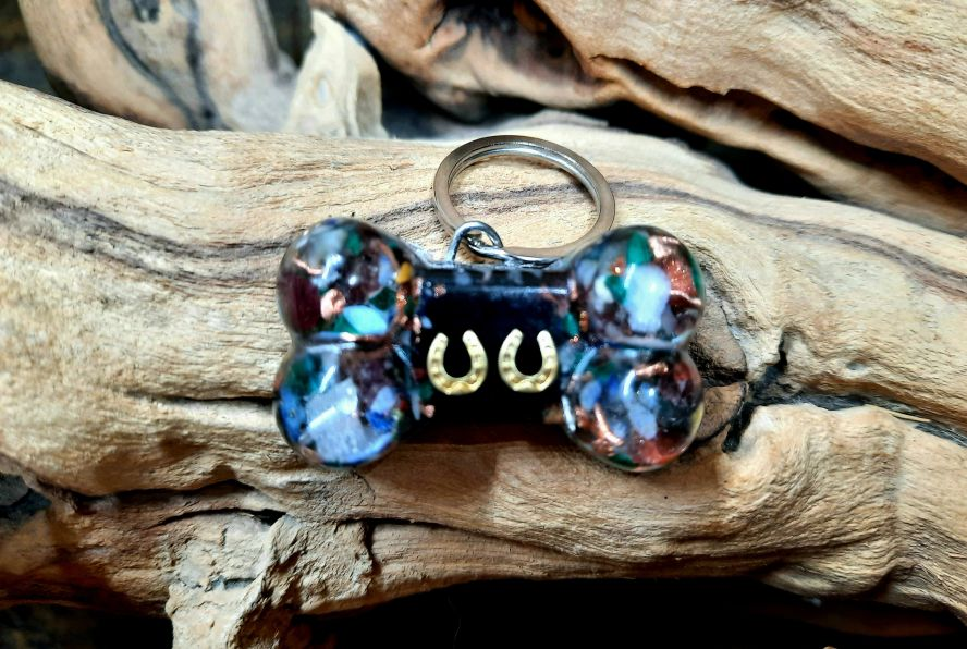 Dog bone pet charm keychain with blue iridescent beads, dark center, and metal ring