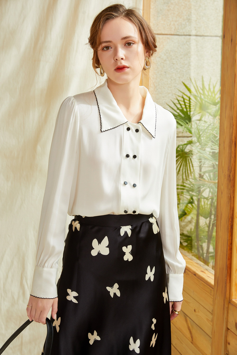 White silk shirt with pointed collar and dark buttons, long sleeves.