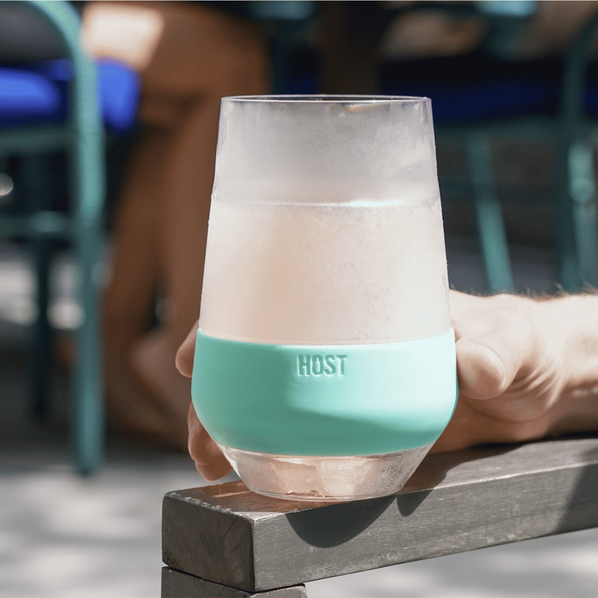 Wine cooling cup held in hand, clear body with mint band, frosty pale drink.