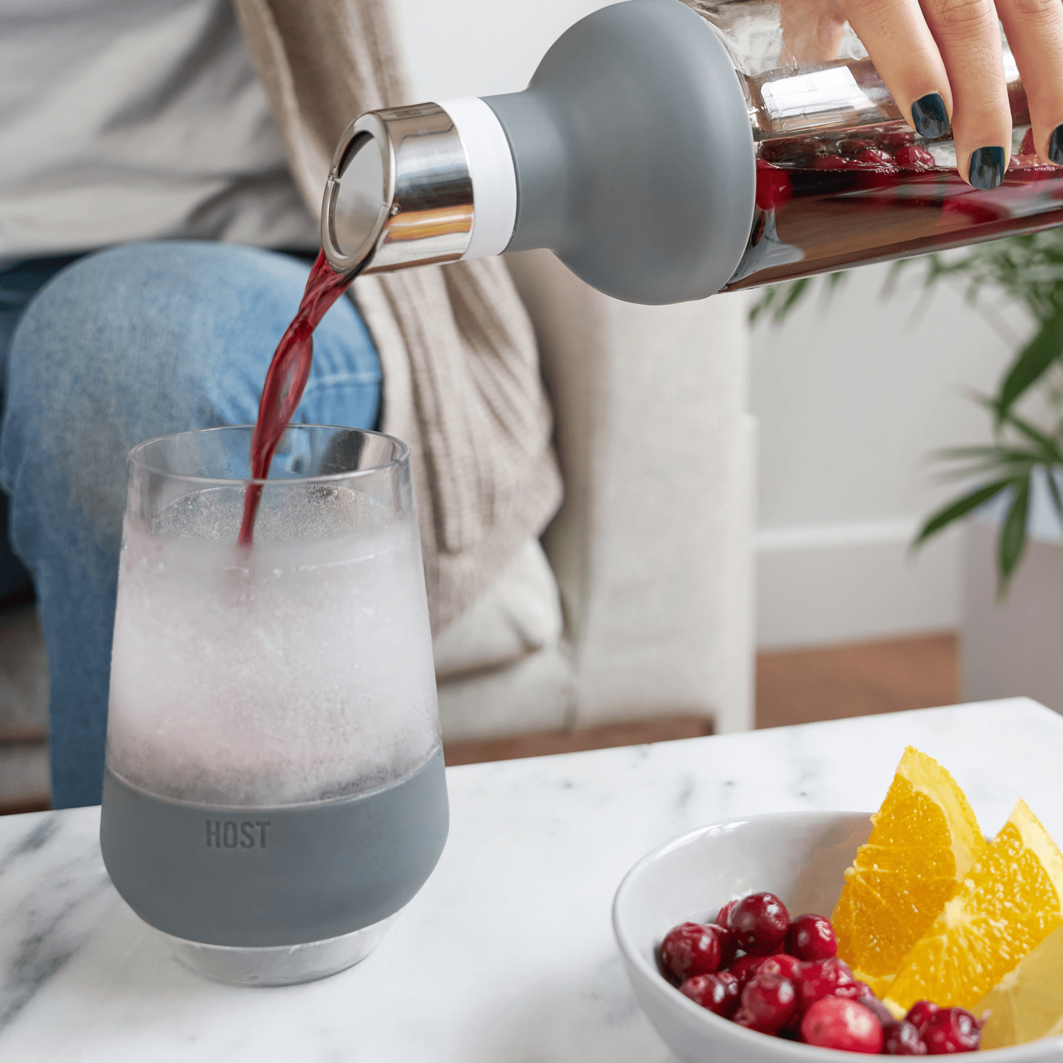 Gray wine cooling cup with clear interior, held while pouring red wine