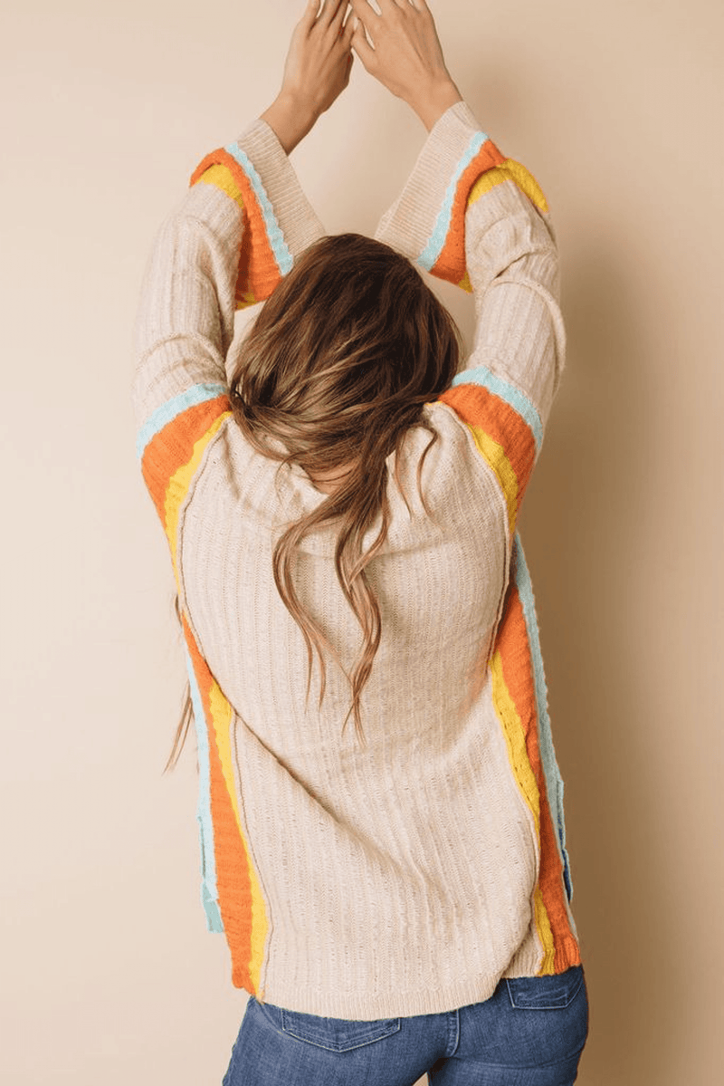 Back view: cream knit sweater with rainbow stripe sleeves and textured knit