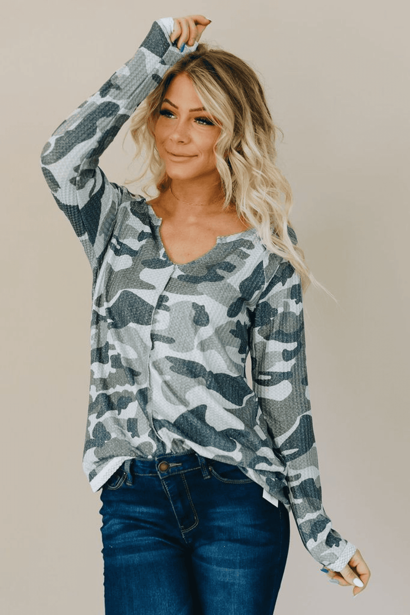 Camo long-sleeve top, scoop neck, front view with raised right arm.