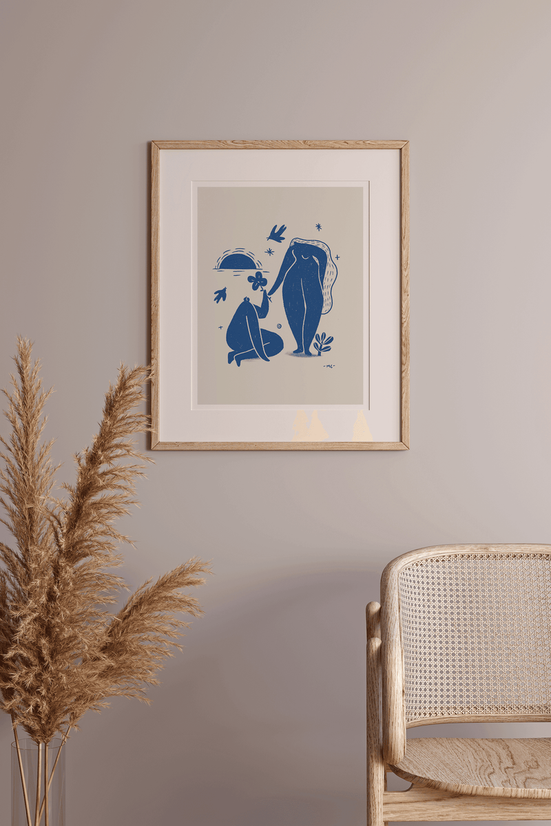 Wood-framed blue line-art print with two figures and star accents, white mat