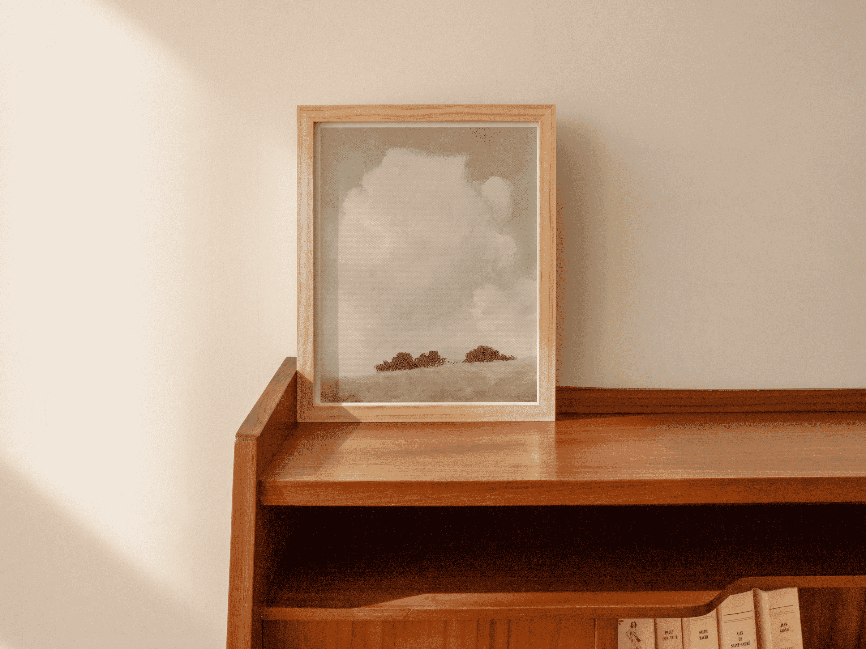 Framed cloud-and-landscape wall art on a wooden shelf