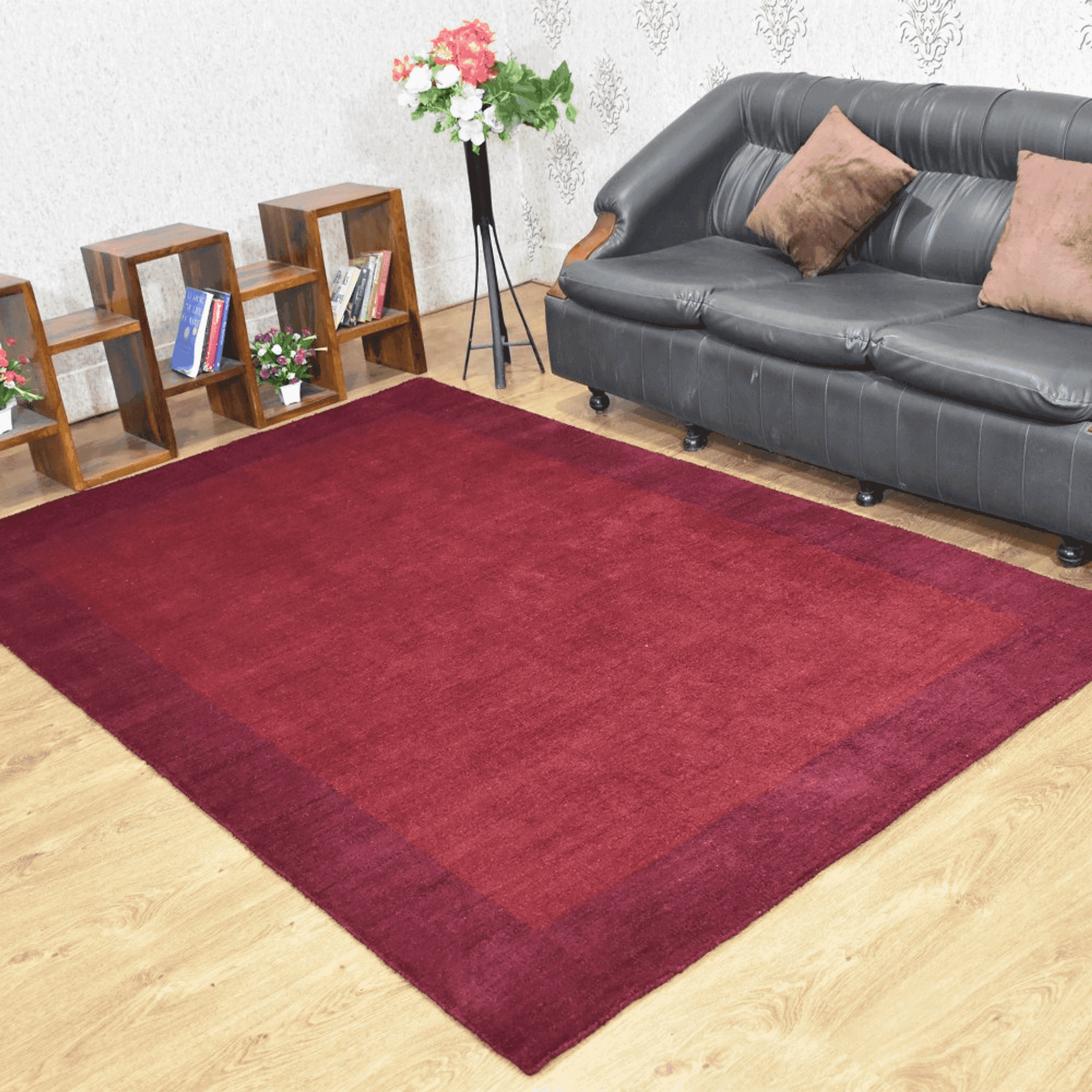 Burgundy area rug with low pile and tidy border, laid flat.