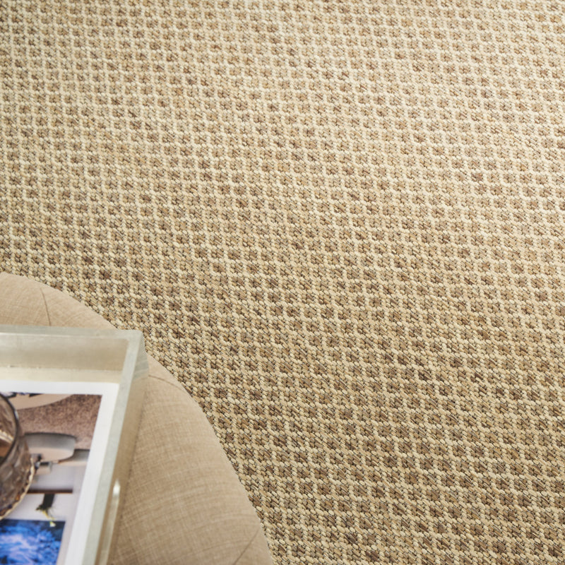 Tan woven area rug edge with textured pile and visible carpet backing