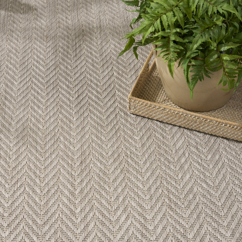 Light gray area rug with textured zigzag chevron pattern and visible corner binding