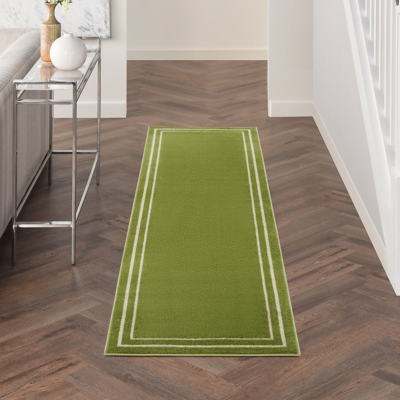 Green indoor outdoor runner rug with ivory border stripe pattern on dark wood floor.