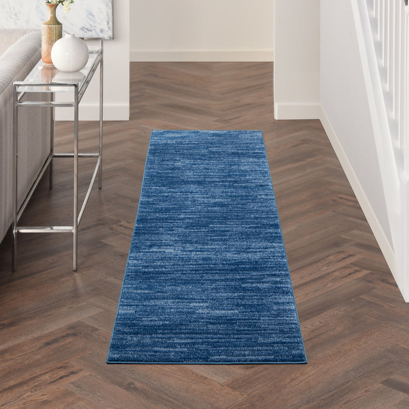 Blue runner rug placed in a hallway on dark wood flooring.