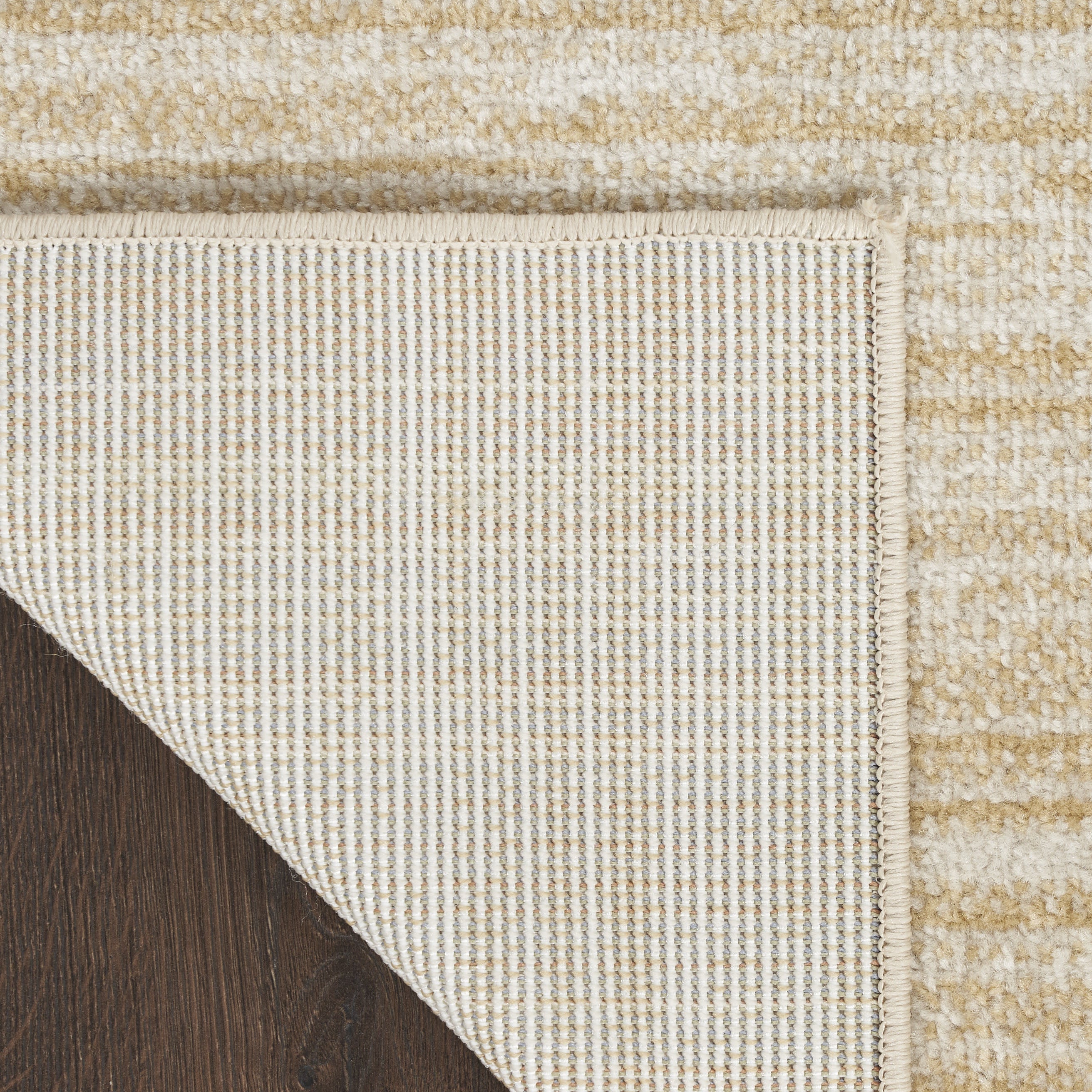 Ivory and gold area rug corner with woven edge and underside backing texture