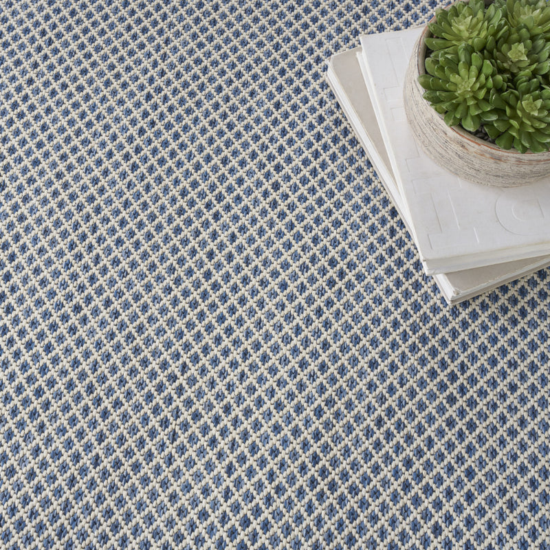 Indoor/outdoor area rug corner with blue-and-ivory diamond weave texture